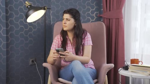 Woman Sits in Chair Using Cellphone