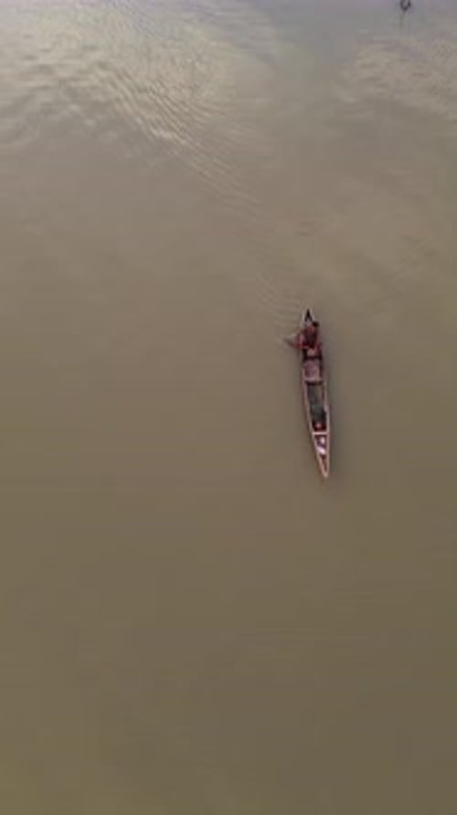 Vertical drone footage of a fisherman on his boat in the lake
