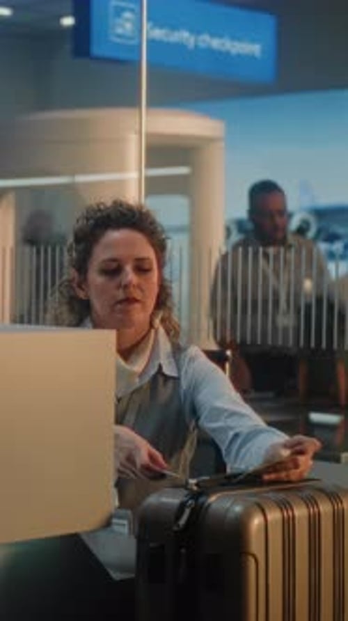 Female Airline Worker Checks in Luggage at Counter Puts Baggage Tag Sticker on Suitcase