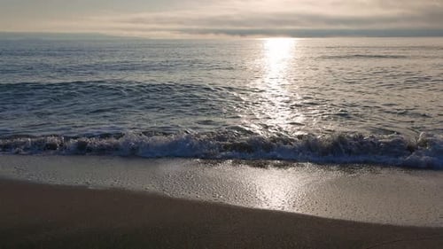 Black Sea and Beach Nearby Against a Sky with Clouds and a Dawn Sun