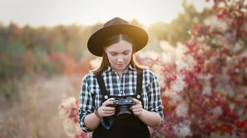 Femme vérifiant des photos sur un appareil photo numérique analogique sur fond d'automne