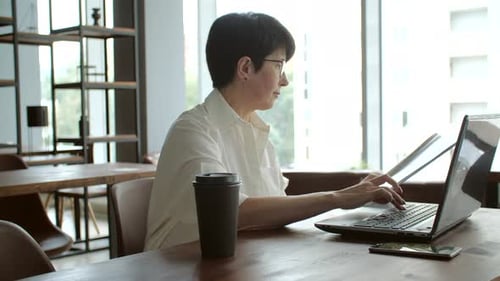 Attractive Mature Businesswoman Working on Laptop in Office or Coworking