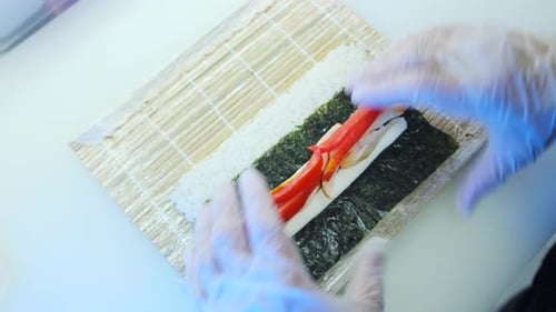Making sushi with bell pepper, chicken fillet, nori seaweed and special rice rolled into a roll