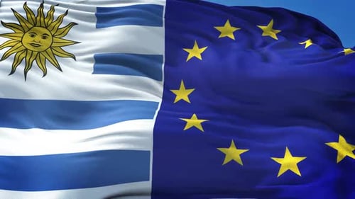 Waving Flags of Uruguay and European Union on Blue Sky