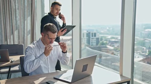 In modern office working with laptop. Young business partners working together.