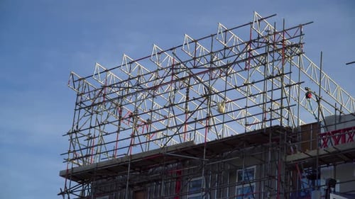 very tall scaffolding on the roof of a building with a bird flying through