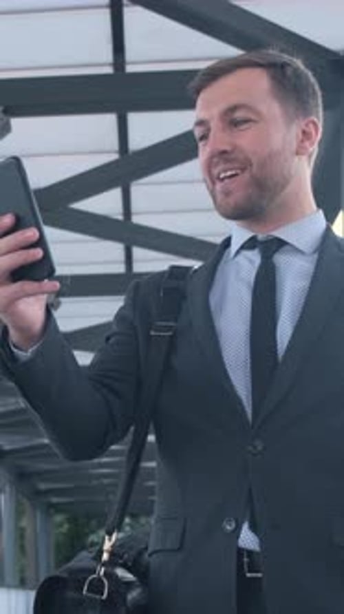 A Businessman at the Airport is Seen Actively Using His Smartphone While Waiting for His Flight