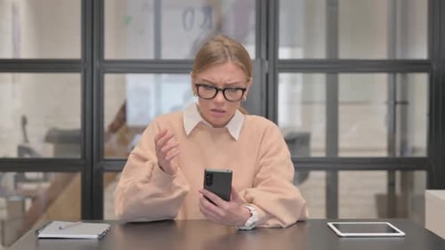 Young Woman Shocked by Loss on Phone in Office