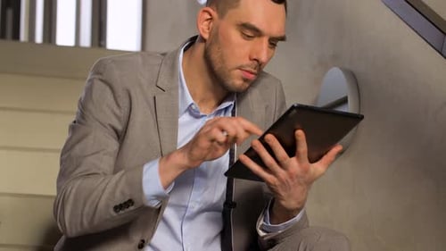 Hispanic businessman browsing tablet app on office stairs connecting online