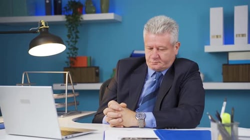 Exhausted Businessman Working at Desk in Office