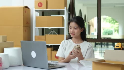 O empreendedor verifica pedidos on-line e embala produtos para clientes em um espaço de trabalho inicial.