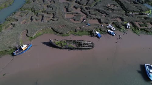Mooring Boats And Shipwreck At Marshes In Tollesbury Marina, Essex, United Kingdom. Aerial Tilt-down