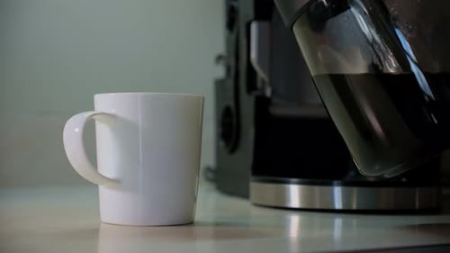 A Hand Pour Coffee in Cup and Takes a White Cup with Coffee From the Table Close Up