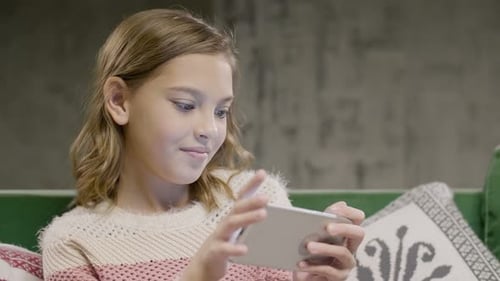 Girl Using a Mobile Phone on a Sofa