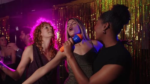 Happy Women Singing Karaoke in Bright Nightclub