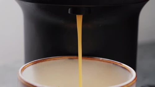 Pouring coffee from coffee machine into cup in coffee shop, close up of preparing espresso coffee.