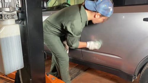 Woman Cleans Car in Auto Repair Shop