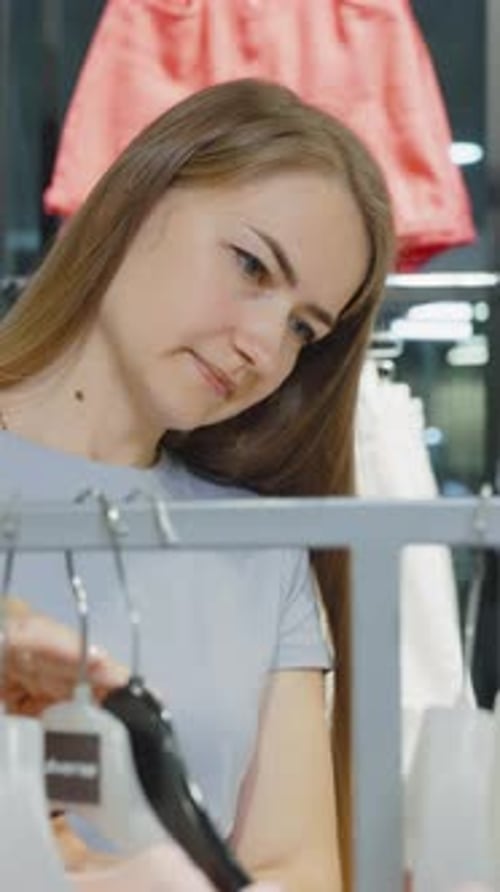 Vertical Screen Caucasian Woman Picking Outfit at Fashion Store
