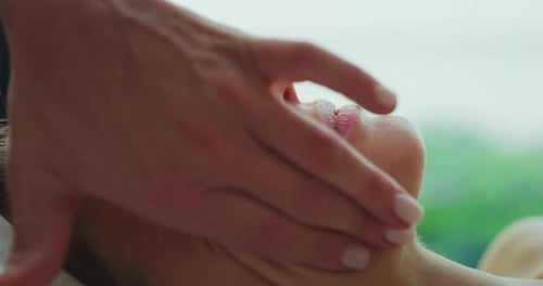 Close up of an young woman with a towel on her head is receiving a facial massage and spa treatmen