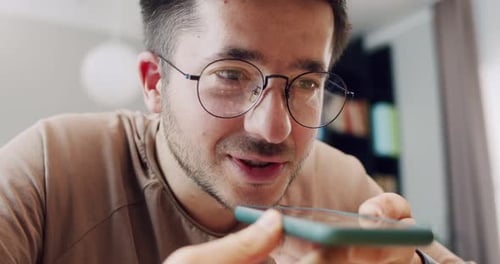 Close Up of Smiling Caucasian Man in Glasses Recording Voice Message on Mobile Phone At Home Indoors