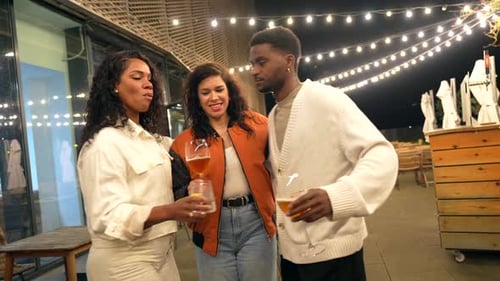 Friends Toasting Drinks Together on Urban Rooftop at Night