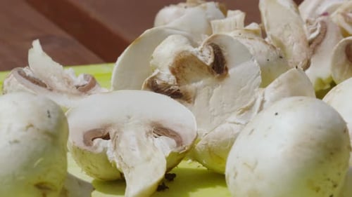 Freshly Cut Baby Button Mushrooms Lying on Chopping Board with Sharp Knife