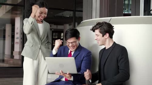 Excited Professionals Celebrate Success Using Laptop