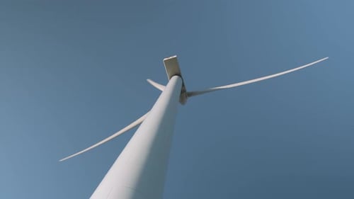 Close up low angle shot of a wind turbine spinning and generating clean energy