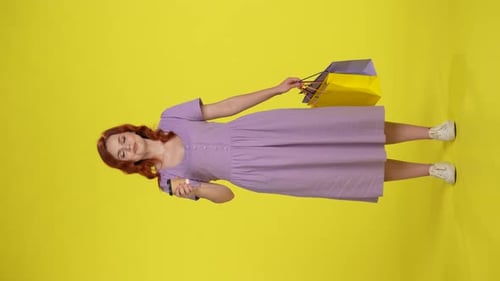Smiling Woman with Shopping Bags on Yellow Background