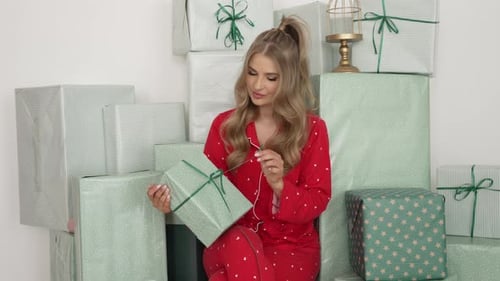 Woman Opens Christmas Gift Surrounded By Wrapped Presents
