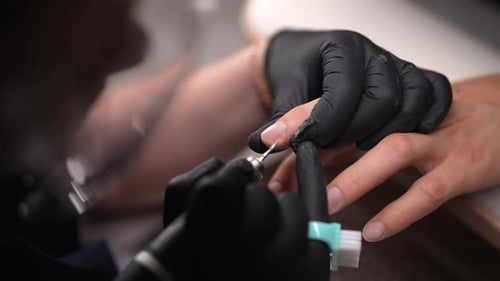 Nail Technician Files Client's Nails Closely