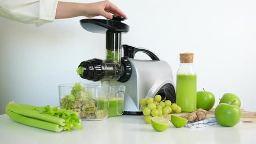 Girl Juices Fresh Celery Juice Through An Auger Juicer