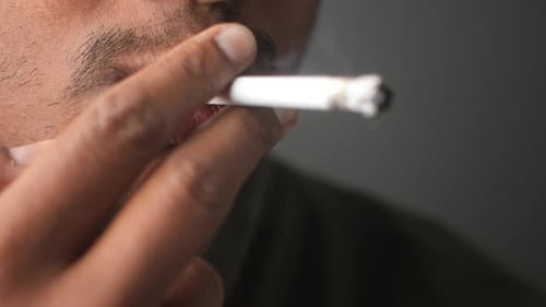 Gros plan d'un homme fumant une cigarette dans un environnement détendu