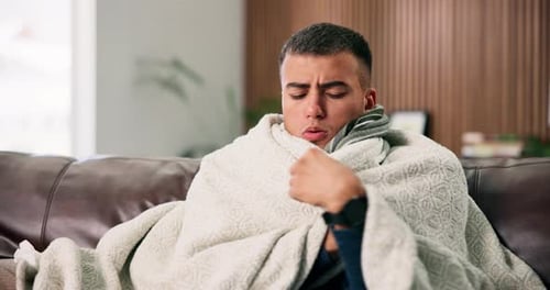 Blanket, cold and snug with man on sofa in living room of home for cozy, comfort or warm in winter
