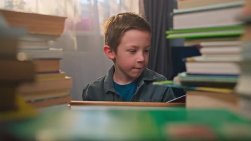 Boy Reads Book Amongst Stacks of Books