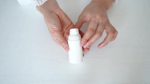 Woman Holding a Small White Lotion Bottle