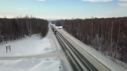 Blick von oben auf die Winterstraße, auf der Autos und Lastwagen fahren