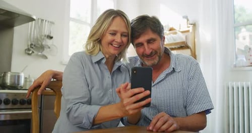 Happy Couple Looking at Smartphone and Laughing