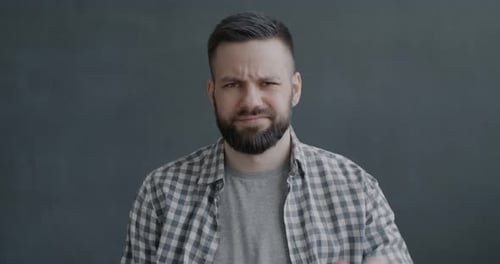 Slow Motion Portrait of Disappointed Young Man Showing Thumbsdown Hand Gesture