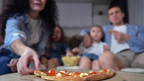 Family Enjoys Pizza Together at Home on Couch