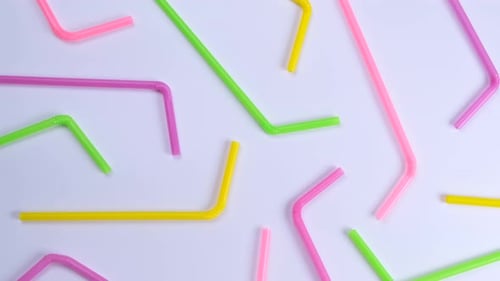 Rotating Multicolored Cocktail Straws on a White Background Top View the Concept of Celebrating a