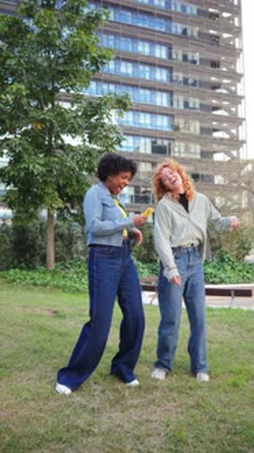 Two Young Women Dancing and Using Mobile Phone Outdoors