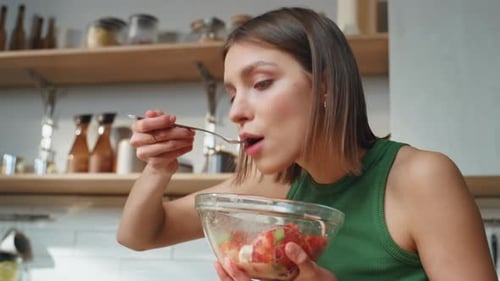 Young Woman Enjoys Fresh Salad in Kitchen