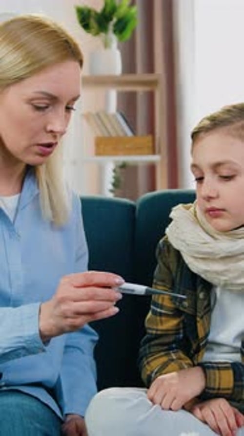 Cute Ill Upset 12Aged Boy with Wrapped Scarf Around Neck Suffers From the Flu Sitting on the Couch