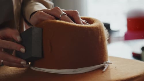 Woman Crafts Beige Hat in Fashionable Workplace