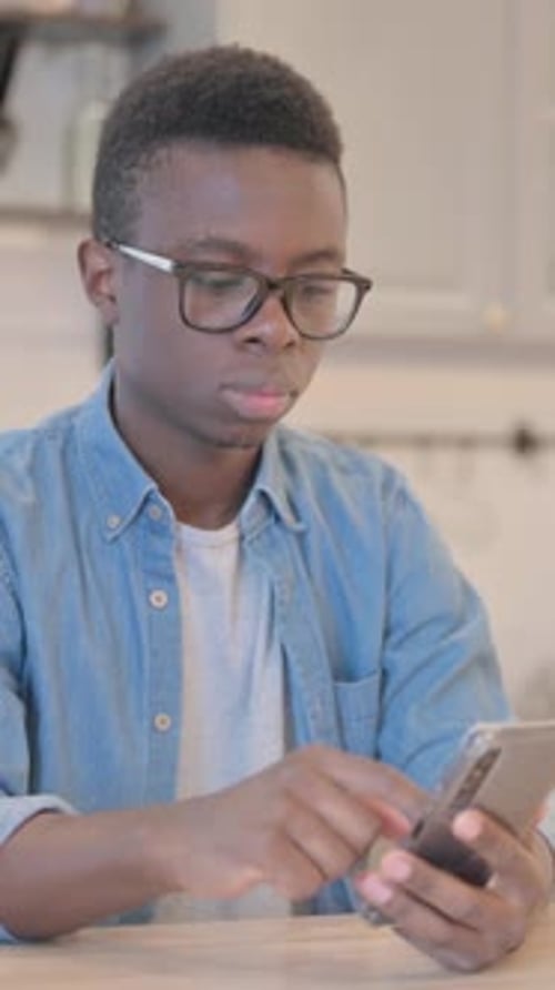 Excited Young Man Celebrates Success Using Smartphone