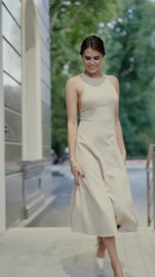 Mulher elegante em vestido bege gira graciosamente na cidade