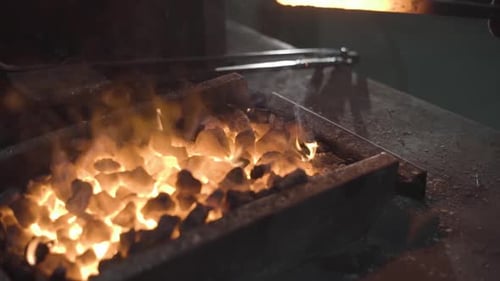 A Blacksmith Works with Metal in a Forge