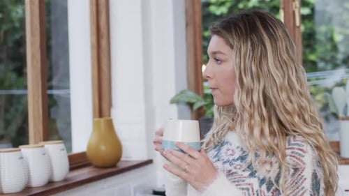 Woman Drinks from Mug in Cozy Kitchen
