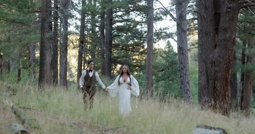 Stylish Couple Walking Through Forest on Wedding Day